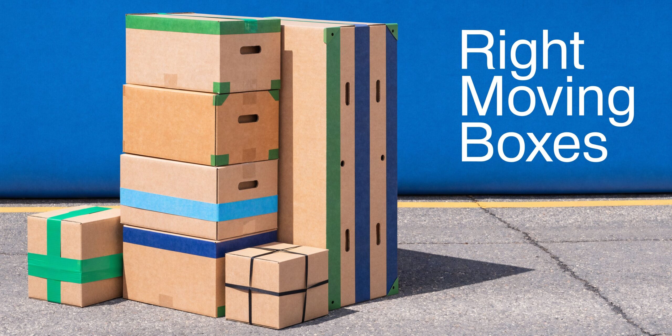 A stack of various cardboard moving boxes of different sizes sitting on asphalt against a blue background.