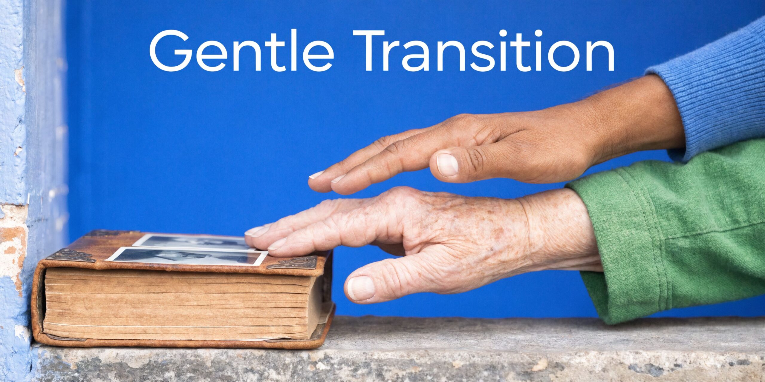 An elderly person and a younger person placing hands gently on an old book with family photos.